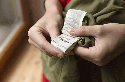 Une personne regarde l'étiquette de lavage de son vêtement